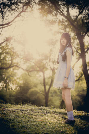 Cute Asian Thai girl is standing in the evening sunset through the wilderness in fairy tale style