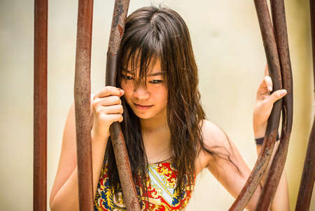 Asian Thai girl is bending the prison bar with her powerの写真素材