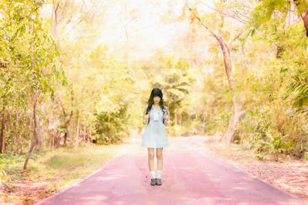 Watercolor illustration of a cute Asian Thai girl in vintage dress is standing on a romantic autumn seanson forest path aloneの写真素材