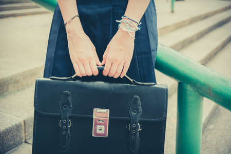Body and hands of cute Asian Thai high schoolgirls student in school uniform holding black leather bag in education fashion in retro vintage childhood  conceptの写真素材