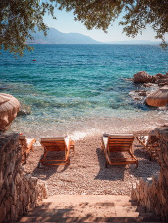 The image showcases a serene coastal setting with several wooden lounge chairs resting on a sandy beach. Turquoise water meets the shore, and the composition features a picturesque view. The sunny daylight enhances the vivid colors, perfect for various commercial or editorial projects.の素材