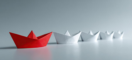 Single red origami boat amongst many white origami boatsの素材
