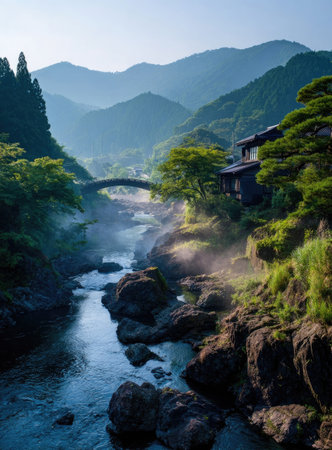Misty mountain valley with a river and bridge. Lush green foliage surrounds a flowing river, with a traditional bridge over itの素材