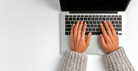 An overhead shot showcases hands typing on a laptop keyboard. The image features a minimalist composition with neutral colors, possibly suggesting a workspace. The lighting appears even, highlighting the keyboard and hands. This image could be used for articles, websites, or advertising projects related to technology.の素材