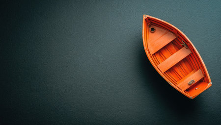 An overhead shot features an orange wooden boat set against a dark, textured background. The boat, with visible planks and benches, evokes a sense of journey and solitude. The composition utilizes copy space, suggesting potential for various commercial applications. The contrasting colors and lighting add visual interest.の素材