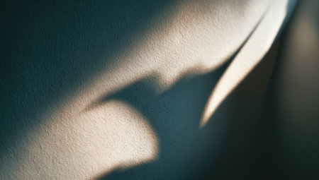 An image showcases an abstract interplay of light and shadow on a textured wall. The composition features a gradient of colors with soft edges and strong contrast, creating a sense of depth. The lighting suggests an interior setting, suitable for visual concepts and backgrounds in various design applications.の素材