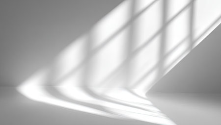 A minimalist composition showcases interplay of light and shadow, forming geometric shapes across a smooth, neutral surface. The image highlights diagonal lines and patterns created by window light. Ideal for design backdrops, product presentations, or creating a clean, modern aesthetic suitable for various applications.の素材