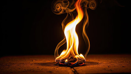 A close-up shot captures a flame burning atop a wooden surface. The fire's bright orange and yellow hues contrast with the dark backdrop, creating a dramatic visual. The composition highlights the flame's shape and the smoke rising from it. This image is suitable for various commercial uses related to energy, danger, and transformation.の素材