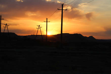 Sunrise shines reflected on golden clouds behind the mountains.