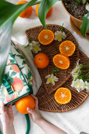 Hand picking orange on a wooden plate.の写真素材