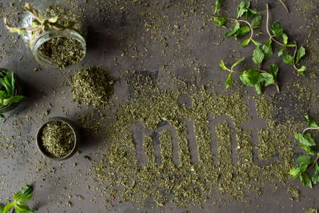 Dried peppermint in a bowl and a bunch of fresh mint scattered on gray concrete background. Top view.の写真素材