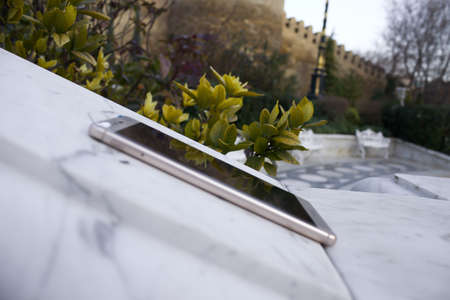 Macro closeup of smartphone, forgotten lying on marble at park