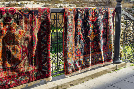 National carpets with Caucasian patterns are for sale in the old town on old stonesの写真素材