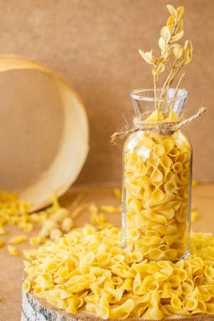 Pasta in a jar, a lot of pasta is scattered around, a jar stands on a wooden stand. High quality photoの写真素材