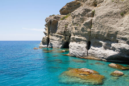 Soft steep pebble rock cliffs towering over the turquoise waters at the south coast of Crete.の写真素材