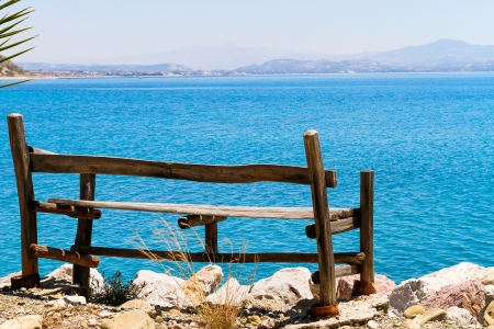 Sea view relaxation wooden bench placed at the top and at the very edge of an elevated stone wall.の写真素材