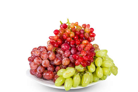Plate of delicious ripe red and white grapes isolated on whiteの写真素材