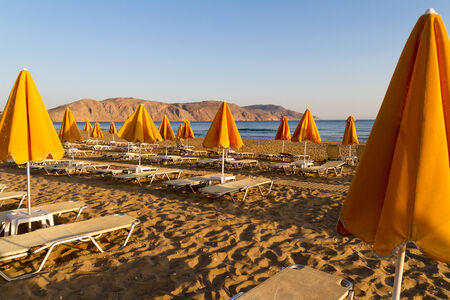 Sun beds and shade unbrellas early morning at a beach on Crete.の写真素材