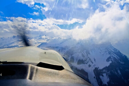 Unique and magnificent airplane aerial view of central snow-capped Swiss Alps, lakes, and blue skies patched with dramatic high cloud formations の写真素材