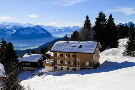 Panoramic skyline view of snow-capped chalets and mountains over foggy Vierwaldstattersee, snow...