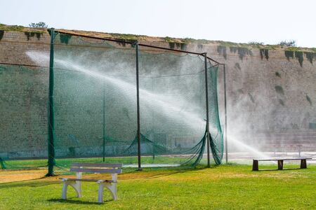 Sprinkler watering the grass of a local sports training stadium.の写真素材