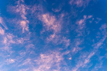 Panoramic view of blue sky with sparse thin orange color delicate near transparent sunset cloudsの写真素材