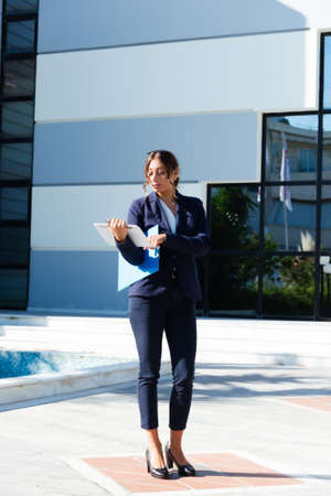 Portrait of young business woman in blue suit standing in front of urban business building.の写真素材