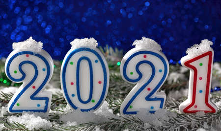 Happy New year Postcard with numbers on spruce branches on the snow and background blue bokeh