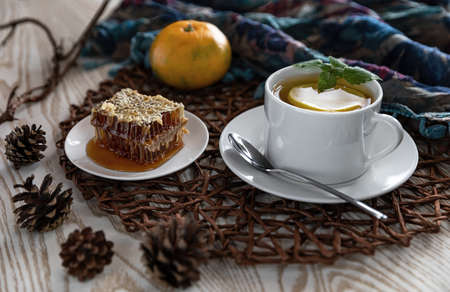 Breakfast with tea and lemon. White tea Cup on a brown woven napkin with honeycombs of buckwheat...