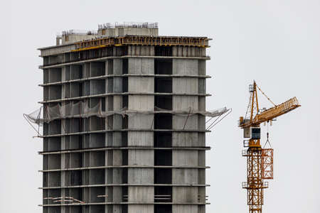 Construction of a new high-rise residential building in the city. A crane works nearby. Businessの写真素材