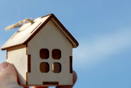 A house in your hand against a blue sky.の写真素材