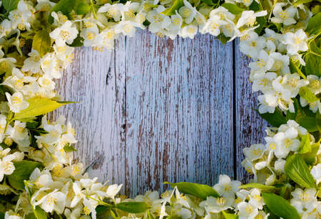 A round frame made of white jasmine flowers on a blue wooden table.