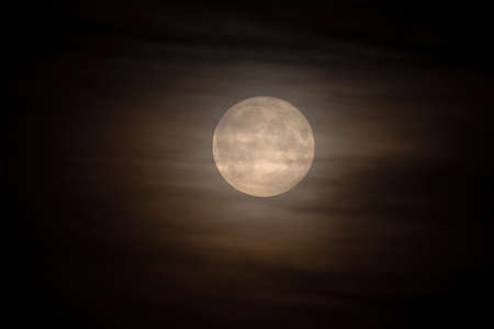 A full yellow moon in the clouds.