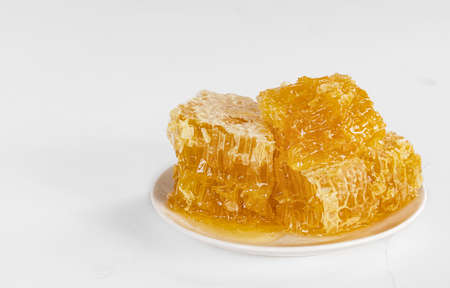 Sweet honey in honeycomb close-up on a white plate and a light background.の写真素材