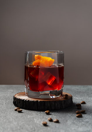Classic cocktail Negroni with gin, red vermouth, orange on a wood desk with a background.