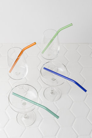 Colorful reusable glass straws in the glass on white background. An alternative replacement for classic disposable plastic drinking straw, eco-friendly, zero waste. Cope space for text.の写真素材