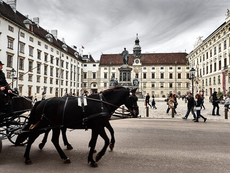 Vienna, Austria - November 1, 2018 - A horse-drawn carriage passing inside the Hofburg palace. People are visiting the palaceのeditorial素材