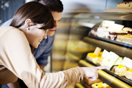 Young woman pointing on cakes in confectioneryの写真素材