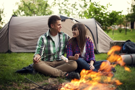 Young couple sitting near a campfire and toasting marshmallowの写真素材