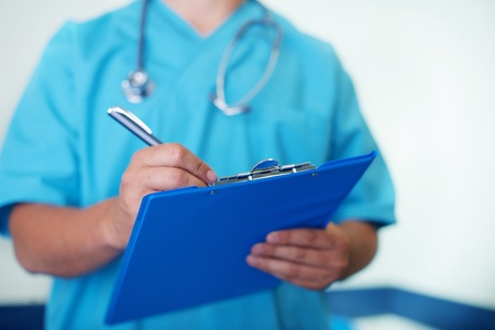 Doctor writing down on medical chartの写真素材