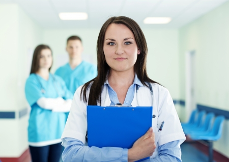 Portrait of young female doctor with interns in backgroundの写真素材