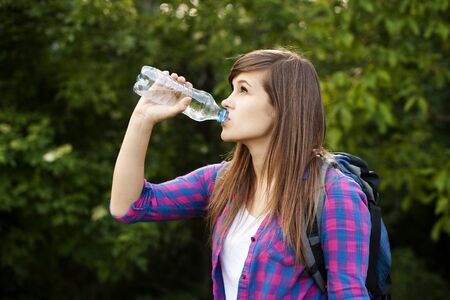 Beautiful female hiker drinking water in forestの写真素材