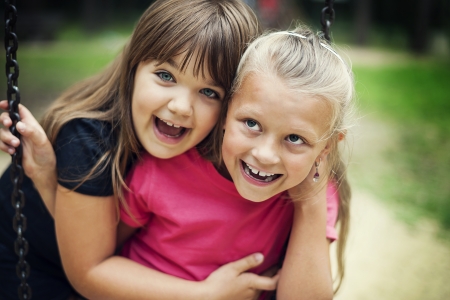 Happy little girls swinging in a parkの写真素材
