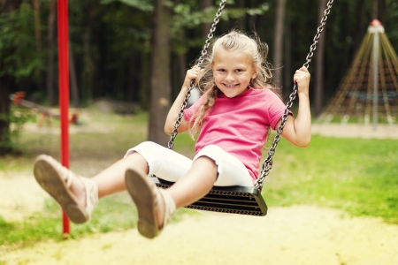 Happy girl swinging on playgroundの写真素材