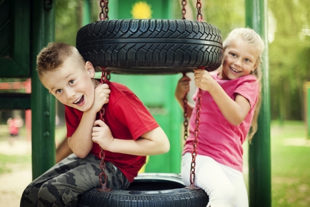 Little girl and boy having fun on playgroundの写真素材