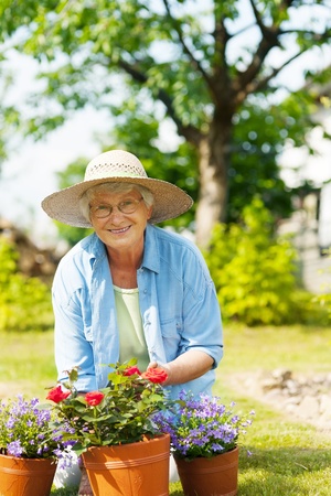 Senior woman with flowers in gardenの写真素材