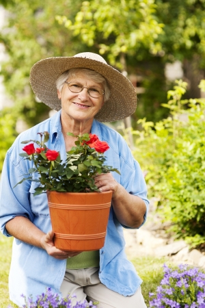 Senior woman with flowers in gardenの写真素材