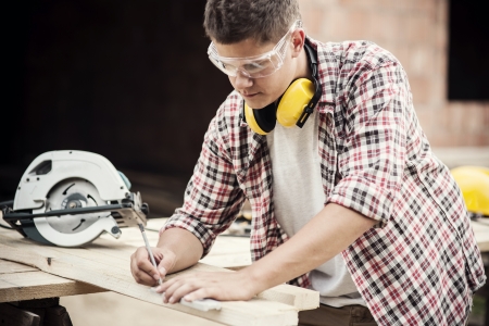 Carpenter measuring a wooden plankの写真素材