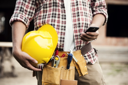Close-up of construction worker texting on mobile phoneの写真素材