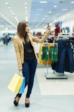 Young woman with shopping bags and mobile phoneの写真素材